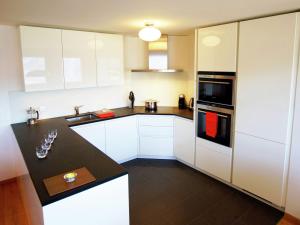 a kitchen with white cabinets and a black counter top at Inviting Holiday Home in Saint-Savinien with bubble bath in Veysonnaz