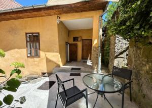 a patio with a glass table and chairs in front of a building at Casa Cojo in Sighişoara