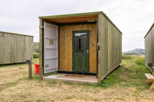 a wooden shed with a green door in a field at Container 2, Camp Tapnell in Yarmouth