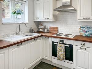 a kitchen with white cabinets and a sink at Rose Cottage in Upper Rissington