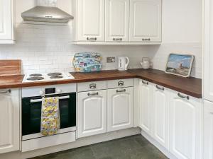 a white kitchen with white cabinets and an oven at Rose Cottage in Upper Rissington