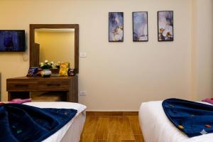 a room with two beds and a mirror and a table at khofo pyramids view in Cairo