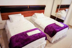 two beds in a hotel room with purple blankets at The Apartments By Sedrah in Irbid