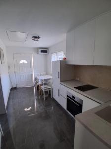 a kitchen with white cabinets and a dining room with a table at Apartment Matija in Stara Novalja +11 photos