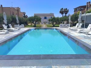a large swimming pool with lounge chairs and a building at Signorino Eco Resort & Spa in Marsala