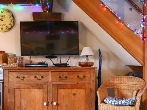 a television on top of a wooden dresser with a chair at Pond Cottage in Alton