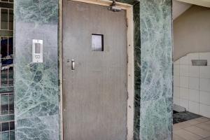 a metal door in a bathroom with a wall at Hotel O Konark Inn in Naroda