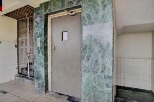 a door in a bathroom with a tile wall at Hotel O Konark Inn in Naroda