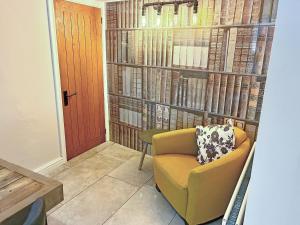 a room with a chair and a wall of books at Cosy Cottage in Portinscale