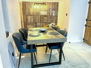 a dining room table with blue chairs in a room at Cosy Cottage in Portinscale