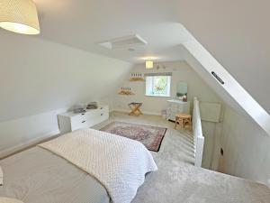 a white bedroom with a bed and a desk at Rectory Cottage in Isham +5 photos