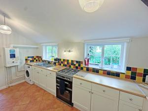 a kitchen with a stove top oven next to a window at Rectory Cottage in Isham