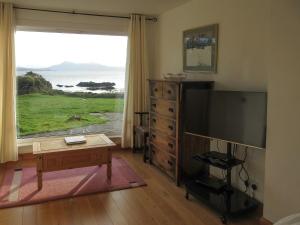 a living room with a large television and a table at South Bay Cottage in Saasaig
