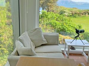 a living room with a couch and a large window at South Bay Cottage in Saasaig