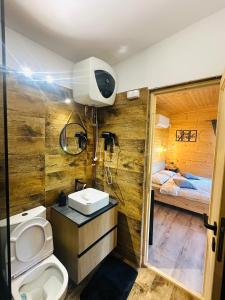 a bathroom with a toilet and a sink and a bed at Wood Nest Curtea de Argeș - Cabană de vacanță în natură in Curtea de Argeş
