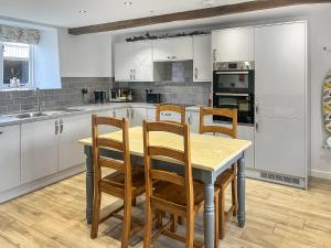 a kitchen with white cabinets and a wooden table and chairs at The Farmhouse - Uk50909 in Thornhaugh