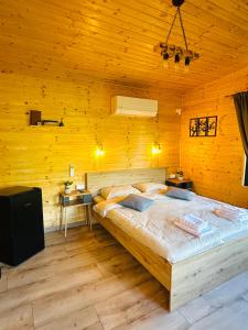 a bedroom with a large bed in a wooden wall at Wood Nest Curtea de Argeș - Cabană de vacanță în natură in Curtea de Argeş