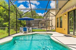 a swimming pool with a table and an umbrella at Family Friendly - South Facing Pool - Game Room - Gated - Near Disney in Davenport