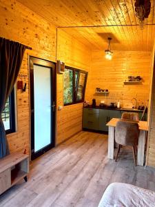 a wooden room with a table and a kitchen at Wood Nest Curtea de Argeș - Cabană de vacanță în natură in Curtea de Argeş +25 photos