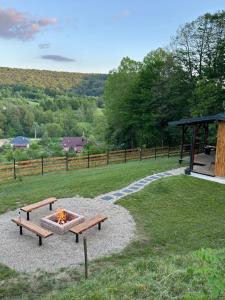 a park with two benches and a fire pit at Wood Nest Curtea de Argeș - Cabană de vacanță în natură in Curtea de Argeş