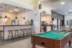 a pool table in a room with a bar at Appart'City Confort Mulhouse in Mulhouse