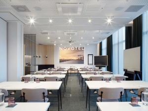 a classroom with white tables and chairs and a screen at Novotel Hamburg Central Station in Hamburg