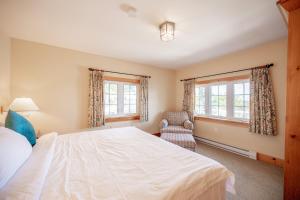 a bedroom with a large white bed and a chair at 136 Birdie Simcoe Cottage private Beach, Kayak in Georgina