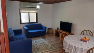 a living room with blue chairs and a table and a television at Little Hula in Yesod Hamaala