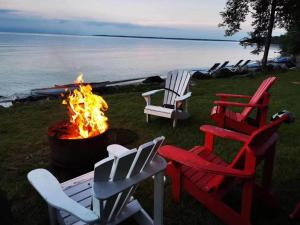 a group of chairs around a fire pit next to the water at 136 Birdie Simcoe Cottage private Beach, Kayak in Georgina