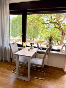 a dining room with a table and chairs and a large window at Uferglanz - Balcony, view, sparkling wine, snacks in Koblenz