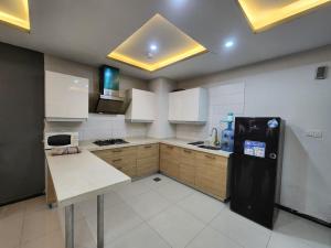 a kitchen with a black refrigerator and white cabinets at Serene Comfort Suites in Rawalpindi +18 photos