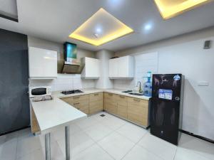 a kitchen with a black refrigerator and white cabinets at Serene Comfort Suites in Rawalpindi