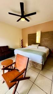 a bedroom with a bed and a fan and a chair at La Casa de las Lunas in Chichén-Itzá