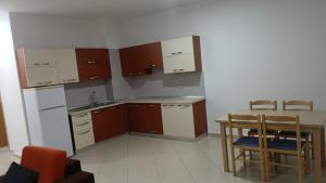 a kitchen with wooden cabinets and a table and chairs at Rana E Hedhun Llugani Apartments in Lezhë