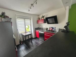 a kitchen with red cabinets and a black floor at Maison avec jardin in Crozon