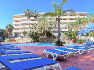 a row of blue lounge chairs next to a swimming pool at Cap Salou Binda Mar Apartment in Salou