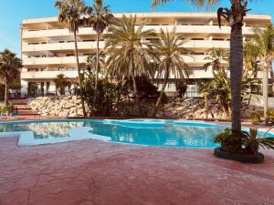 a swimming pool in front of a building with palm trees at Cap Salou Binda Mar Apartment in Salou