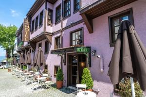 ein lila Gebäude mit Stühlen und Sonnenschirmen davor in der Unterkunft Armistis Hotel in Mudanya