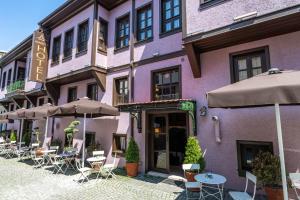 ein lila Gebäude mit Tischen, Stühlen und Sonnenschirmen in der Unterkunft Armistis Hotel in Mudanya