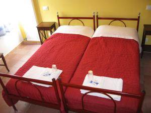 ヴィチェンツァにあるB&B Vaca Moraのベッド2台(赤いシーツ、白いタオル付)