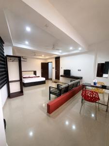 a living room with a red couch and a bed at Grand Munnar Rooms in Munnar