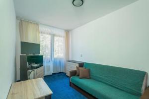 a living room with a green couch and a table at Pensjonat Pod Lwem in Niechorze