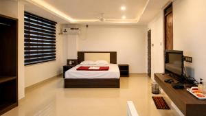 a bedroom with a bed and a flat screen tv at Grand Munnar Rooms in Munnar