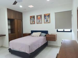 a bedroom with a bed and some pictures on the wall at Departamento comodo en Ubicacion Privilegiada in Mérida