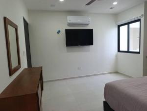 a bedroom with a bed and a tv on the wall at Departamento comodo en Ubicacion Privilegiada in Mérida