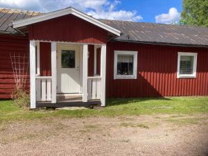 a red house with a white door and two windows at Liten lägenhet i Öje in Öje