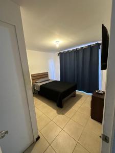 a bedroom with a bed and blue curtains and a television at Casa & Habitaciones in Mejillones