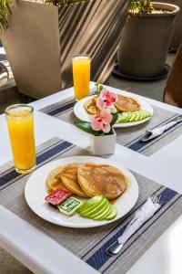 two plates of pancakes on a table with orange juice at AM Hotel y Plaza in Santa Cruz Huatulco
