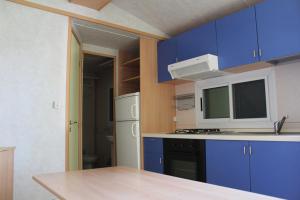 a kitchen with blue cabinets and a white refrigerator at Villaggio Camping Nurral in Fertilia