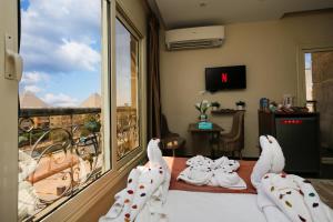 a room with two swans sitting on a bed looking out the window at Hammis Pyramids View INN in Cairo